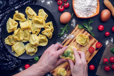 Men's hands prepare italian pasta with ingredients. gastronomic concept
