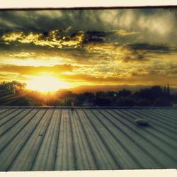 Scenic view of landscape against cloudy sky at sunset