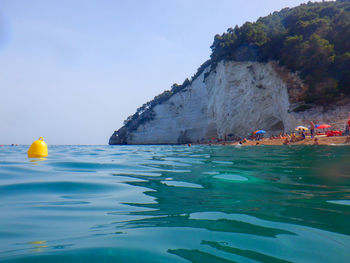 People swimming in sea against sky