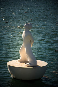 Side view of young woman sculpture by lake