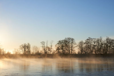 Scenic view of lake against clear sky during sunset