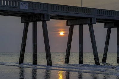 Bridge over sea against sky during sunset