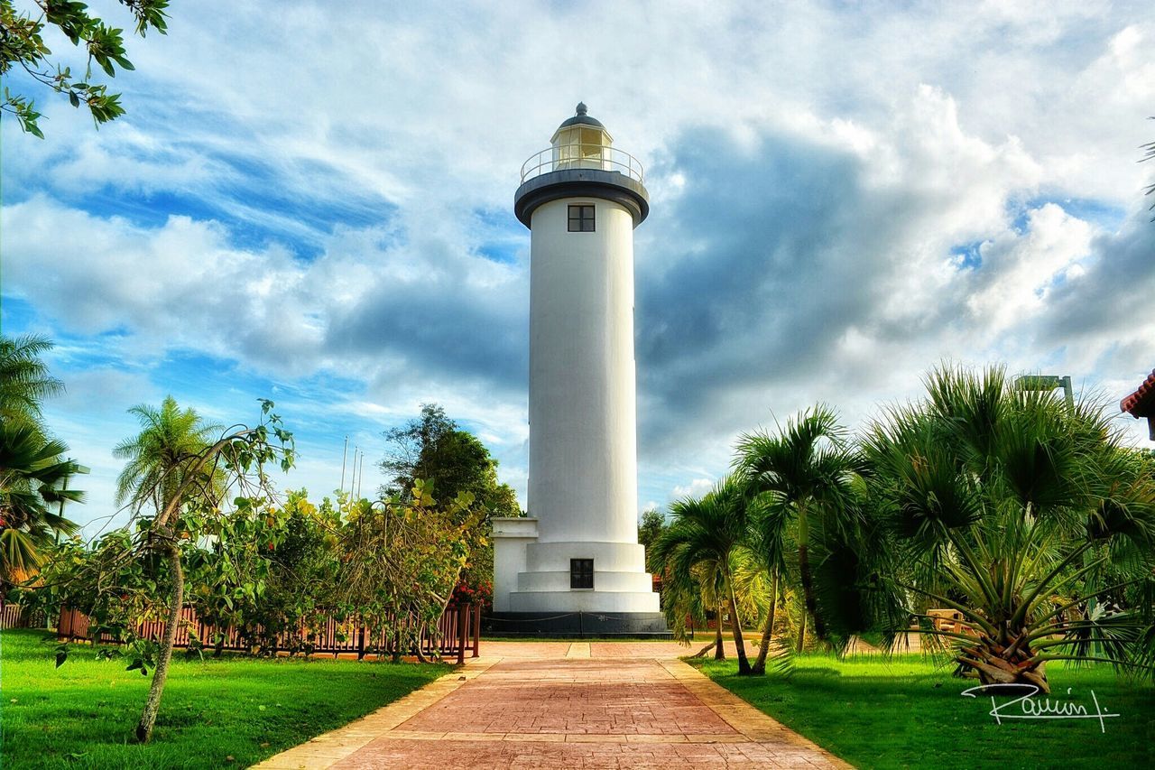 built structure, architecture, sky, tree, building exterior, lighthouse, grass, tower, cloud - sky, tall - high, guidance, cloud, green color, direction, footpath, the way forward, travel destinations, cloudy, day, growth