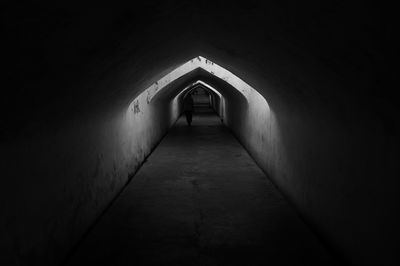 Silhouette person walking in tunnel