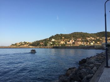 Scenic view of sea by buildings against clear blue sky