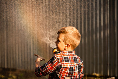 Side view portrait of boy standing against blurred background