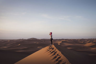 Man standing on sand dune against sky