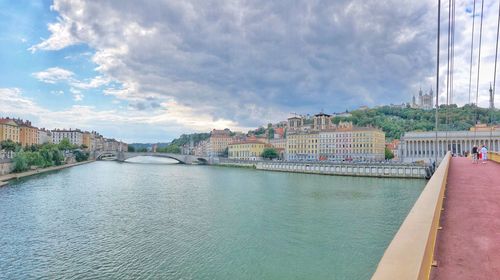 Bridge over river amidst buildings in city against sky