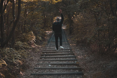 Rear view of woman standing on staircase in forest