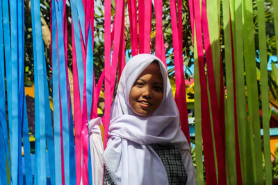 Portrait of happy teenage girl in traditional clothing standing amidst multi colored decoration