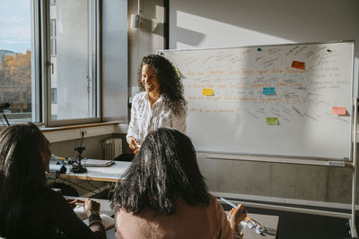 Cheerful professor teaching students sitting in classroom at university