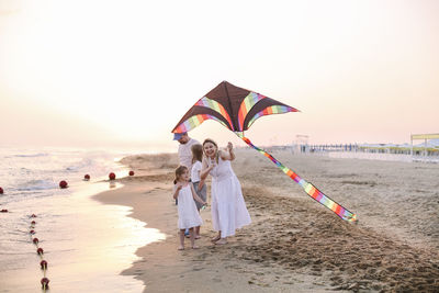 Mother and daughter flying kites on beach