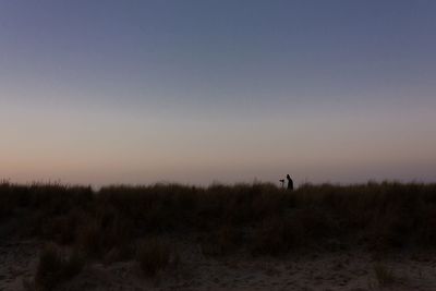 Man standing on field against sky during sunset