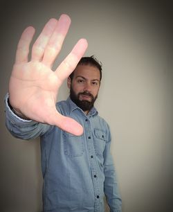 Portrait of young man standing against wall