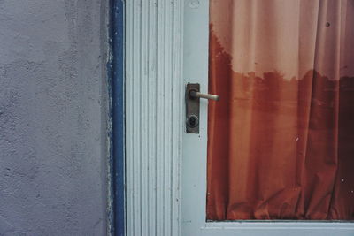 Close up of outdoor door, handle, pane of glass covered with red fabric