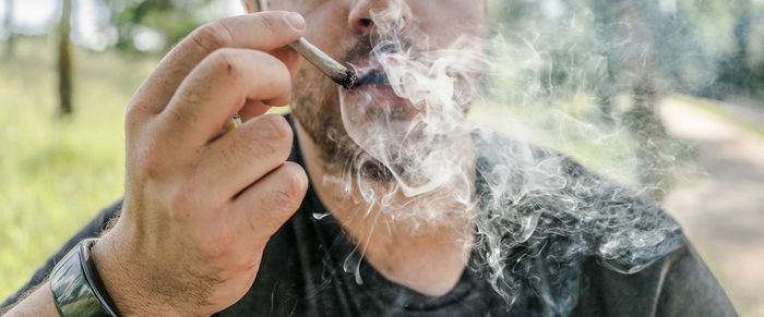 Midsection of man smoking cigarette