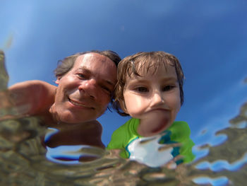 Portrait of father with daughter against blue sky