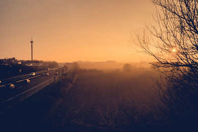 High angle view of field by highway against clear sky during sunrise