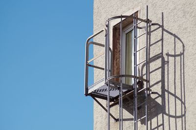 Low angle view of security camera against clear blue sky