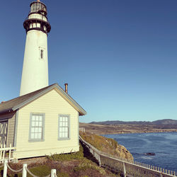 Lighthouse by building against sky