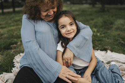 Portrait of smiling girl sitting with grandmother at park