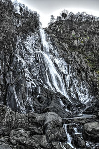 Scenic view of waterfall in forest against sky