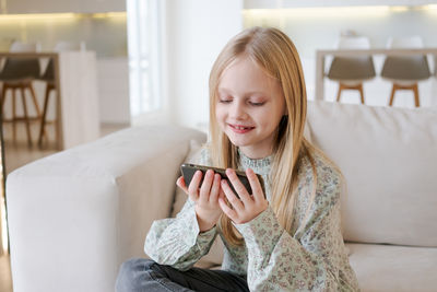 Young woman using mobile phone while sitting on sofa at home