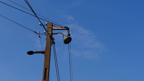 Low angle view of electricity pylon against blue sky