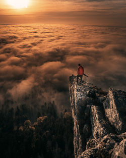 Man standing on rock against sky during sunset