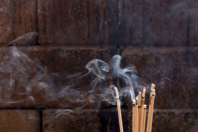 Close-up of burning candles on wood against temple