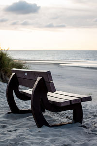 Empty deck chairs on beach against sky