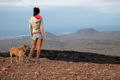 Rear view of woman with dog looking at landscape 