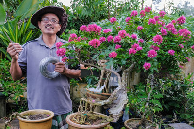 Portrait of smiling woman holding flowering plants