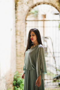 Portrait of young woman standing against wall