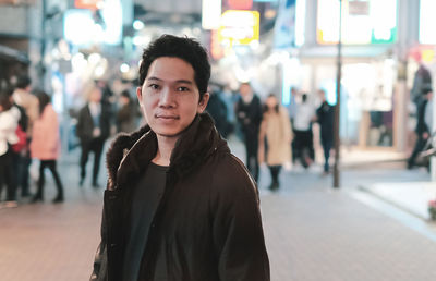 Portrait of young man standing on street in city