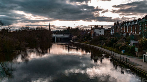 Bridge over river amidst buildings in city against sky