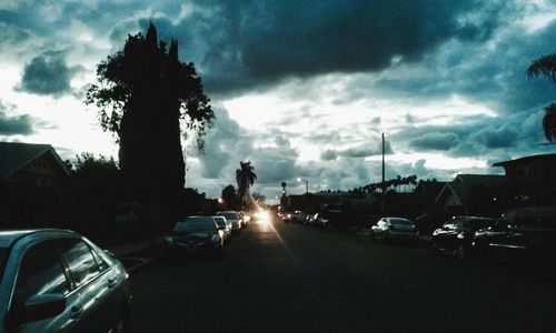 Cars on road against cloudy sky