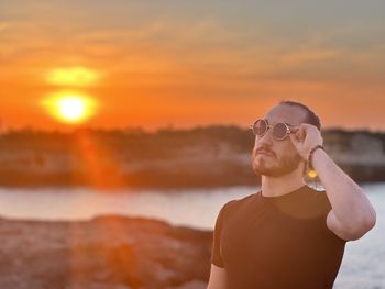 Young man wearing sunglasses while standing against sky during sunset 4