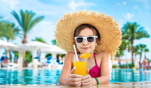 Portrait of girl with orange glass at poolside
