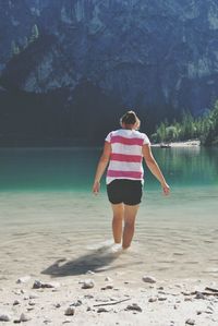 Rear view of woman standing in front of lake