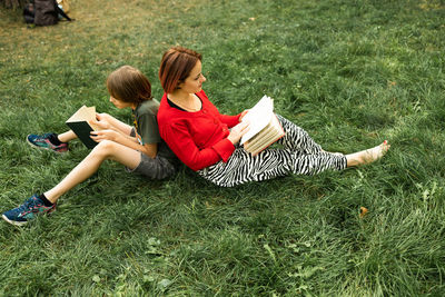 Young woman using mobile phone while sitting on grassy field