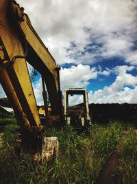 View of machinery on grass against cloudy sky