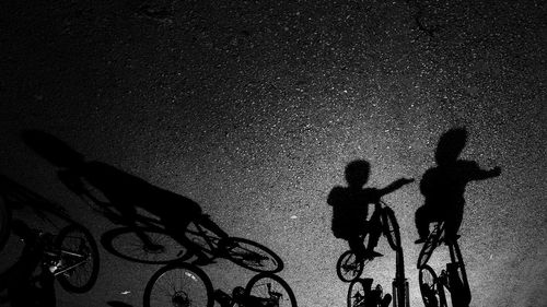 Shadow of boys riding bicycles on street during sunny day