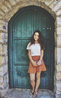 Portrait of young woman standing against closed door