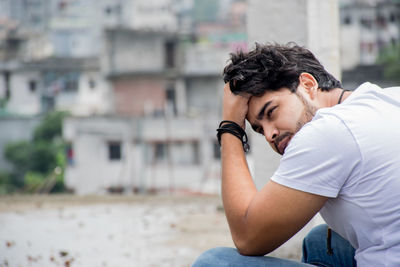 Side view of young man sitting in city