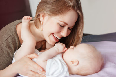 Smiling young woman with baby girl in bedroom at home