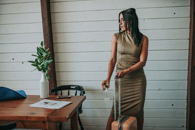 Woman with luggage having wine at home