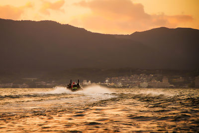 Bass boat on the lake against sky during sunset