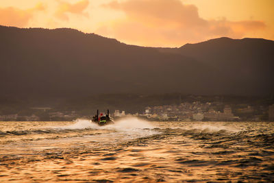 Bass boat on the lake against sky during sunset