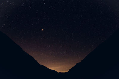 Low angle view of silhouette mountain against sky at night